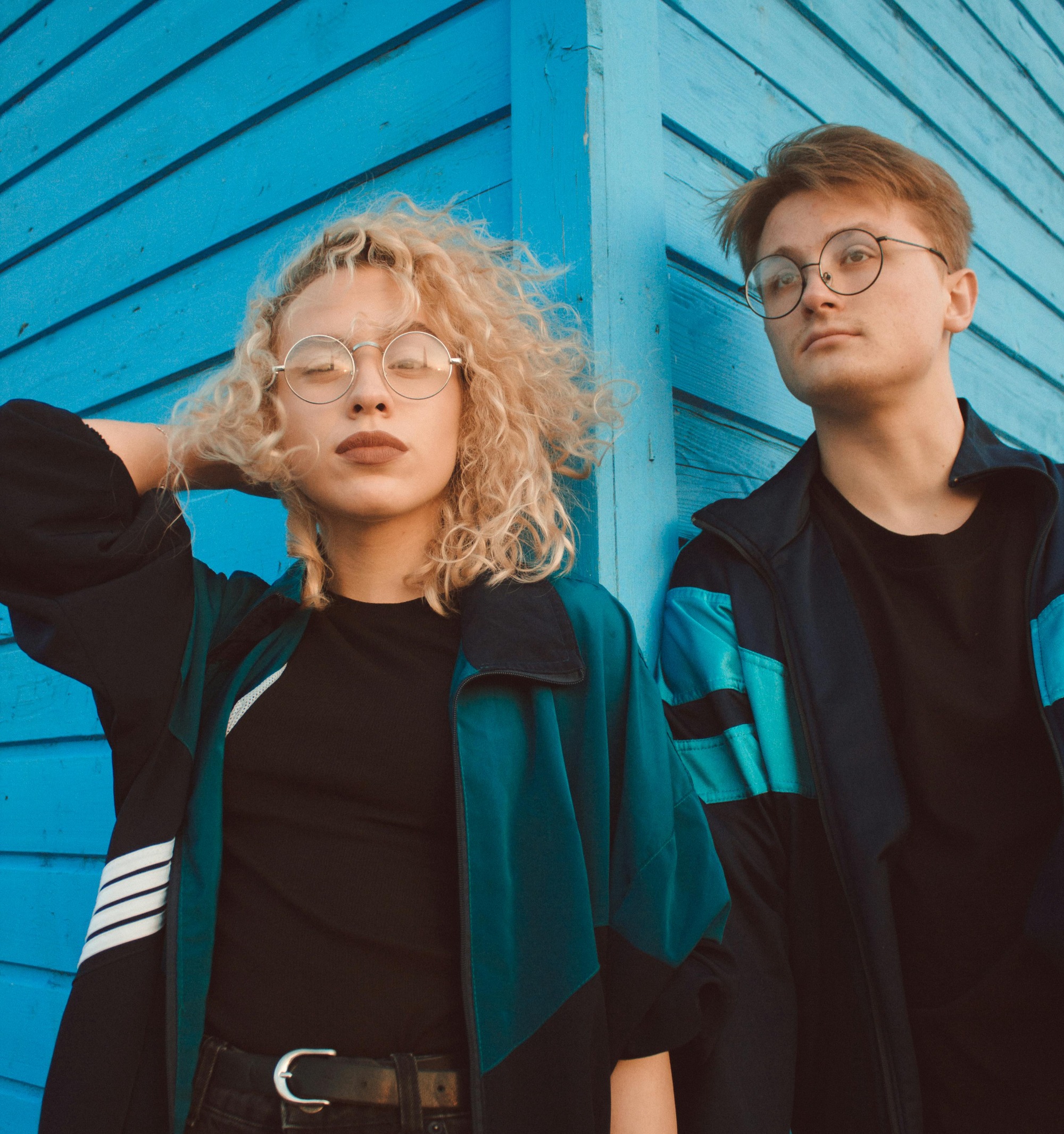 girl and boy in blue jacket next to blue wall
