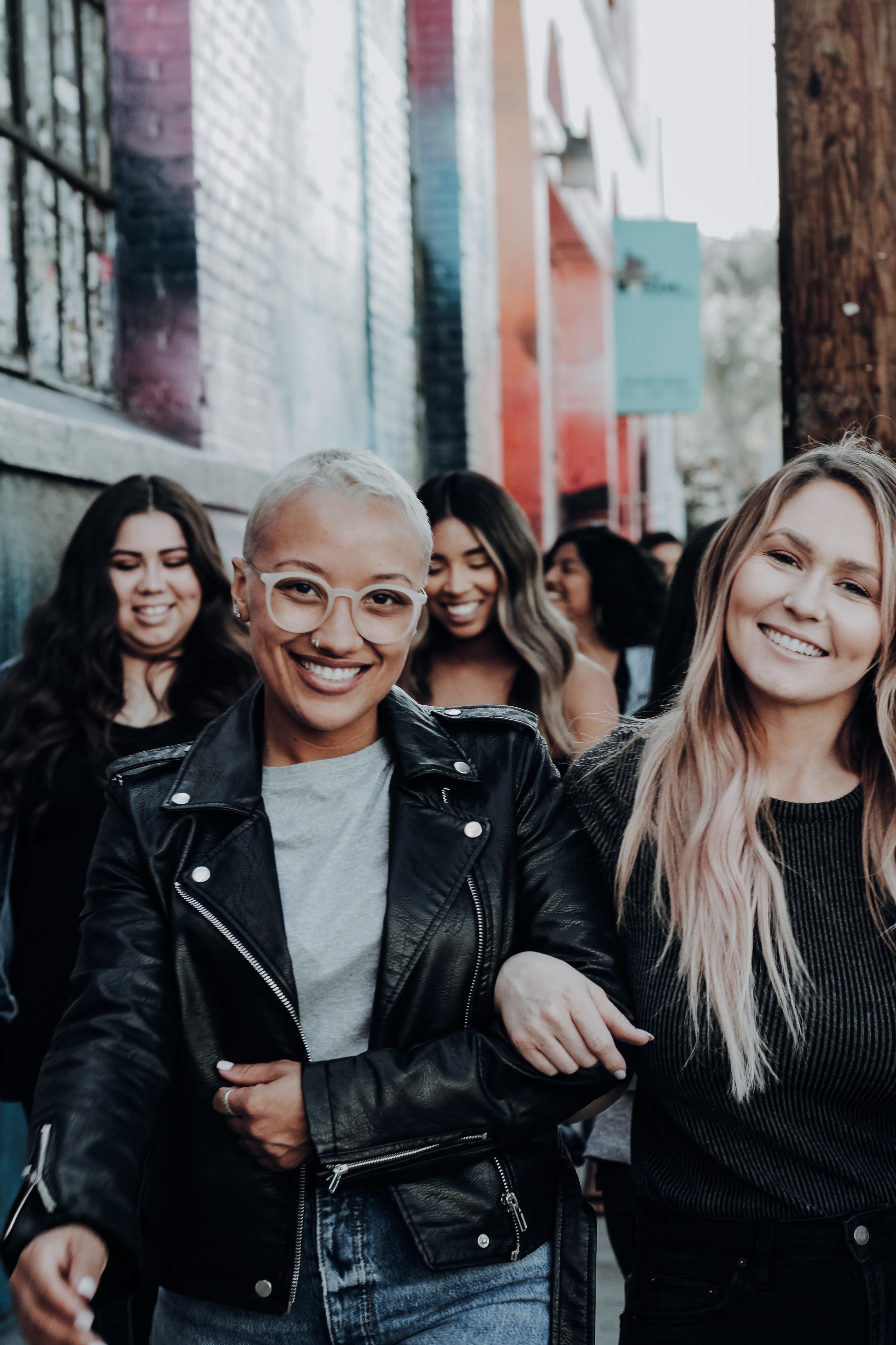 two girls walking arm in arm with other girls in back