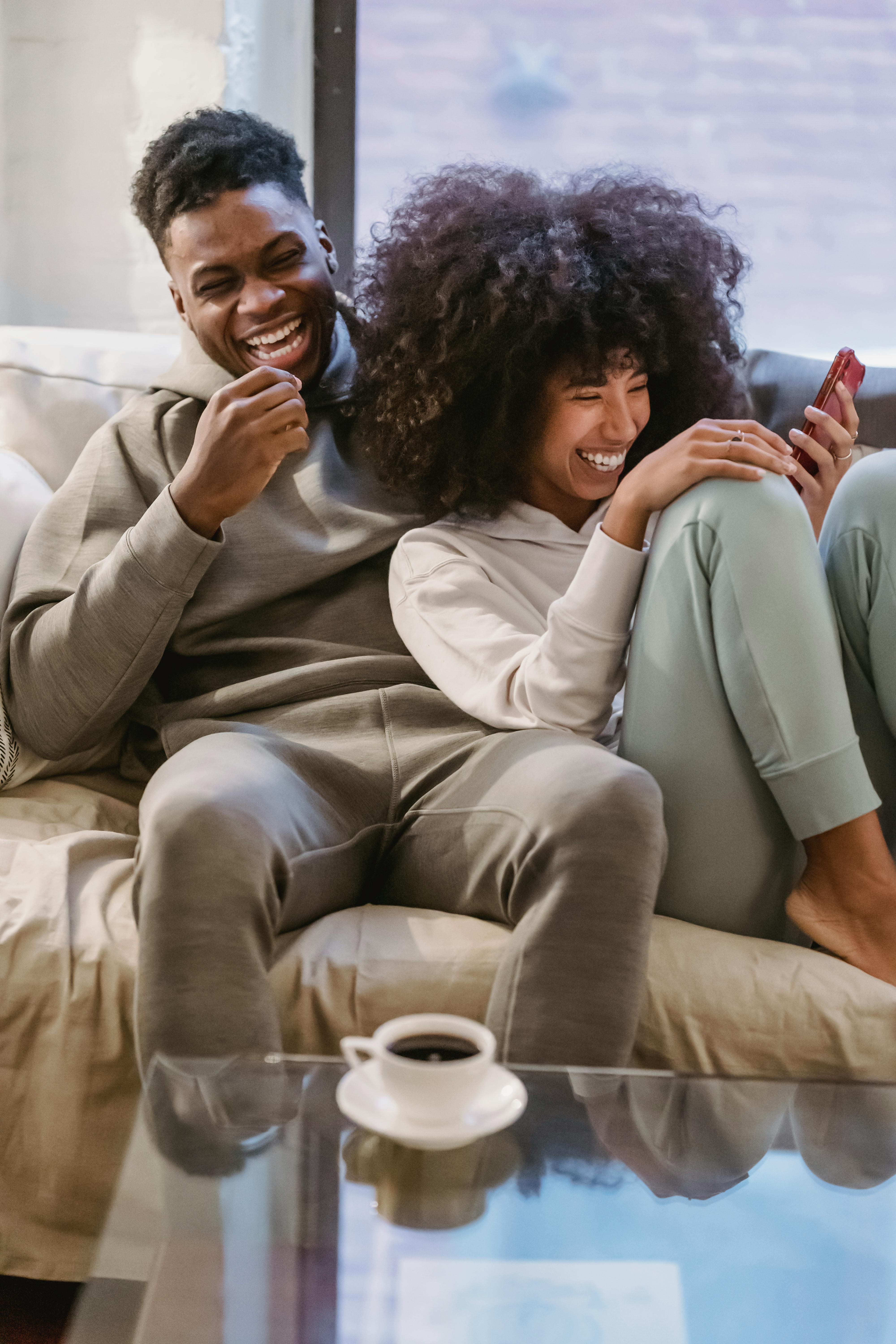 couple hanging out on couch looking at phone 